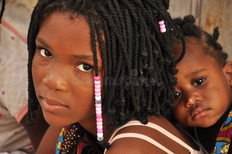 Beautiful black girl with sister on her back in Mozambique, with traditional african hair style. Beautiful black girl with sister on her back in Mozambique, with traditional african hair style