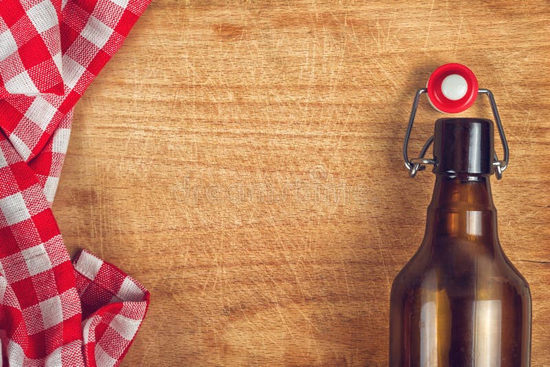 Empty Beer Bottle with Swing Flip Top Stopper on Wooden Table with red and White Checkered Tablecloth and Copy Space. Empty Beer Bottle with Swing Flip Top Stopper on Wooden Table with red and White Checkered Tablecloth and Copy Space