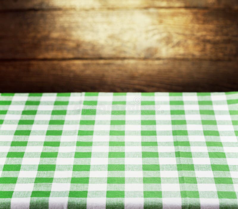 Checkered green tablecloth over rustic wooden background. Checkered green tablecloth over rustic wooden background