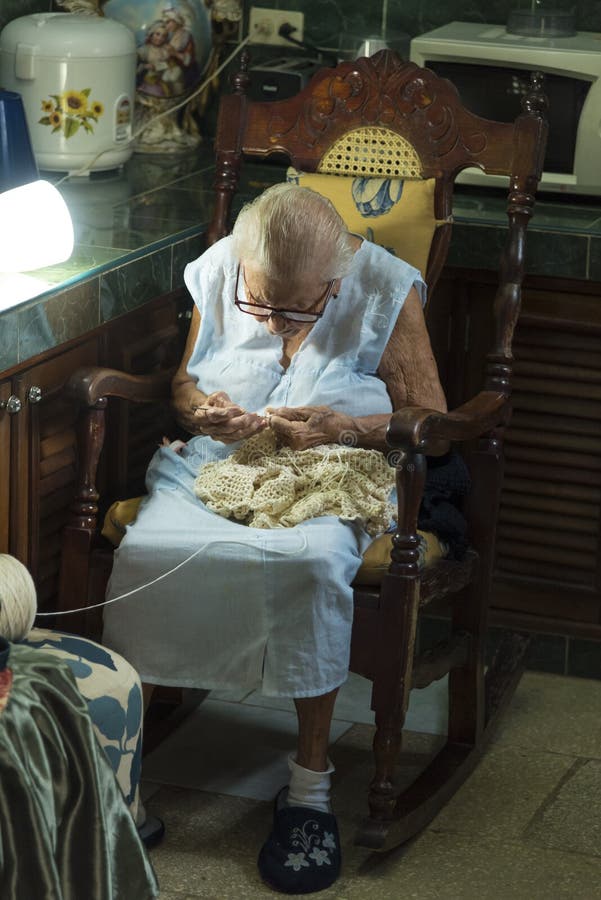 Old Cuban lady sitting in rocking chair in the kitchen working with her knitting. Havana, Cuba. Citizens of Havana is called Habaneros in Spanish. Old Cuban lady sitting in rocking chair in the kitchen working with her knitting. Havana, Cuba. Citizens of Havana is called Habaneros in Spanish.