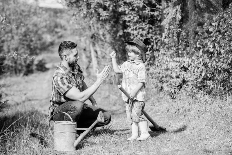 E Attrezzatura di giardino padre e figlio in cappello da cowboy sul ranch Azienda agricola di Eco Giornata per la Terra felice fa immagini stock libere da diritti E Attrezzatura di giardino padre e figlio in cappello da cowboy sul ranch Azienda agricola di Eco Giornata per la Terra felice fa immagini stock libere da diritti