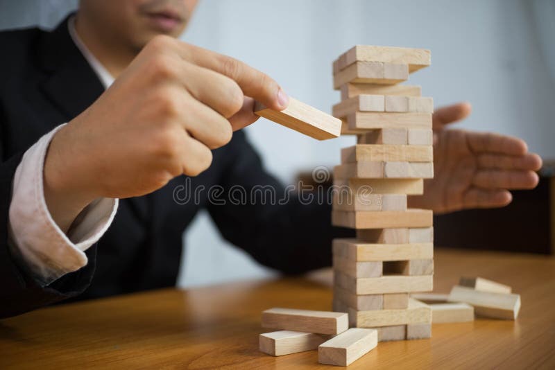 Des hommes d'affaires choisissent des blocs de bois pour compléter les dominos manquants et empêcher le domino de tomber. Concept photo libre de droits