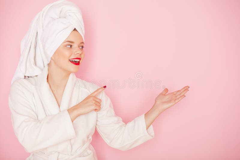 Beauty Young woman with red lips standing in the bath robe and towel on the head on the pink background. Studio shot. Copyspace. Beauty Young woman with red lips standing in the bath robe and towel on the head on the pink background. Studio shot. Copyspace
