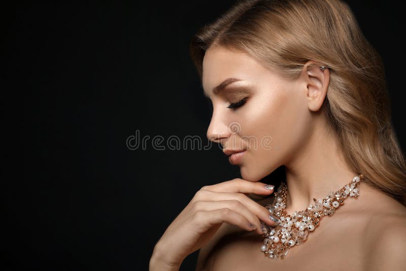 Hermosa joven con joyas elegantes sobre un fondo oscuro imagen de archivo libre de regalías
