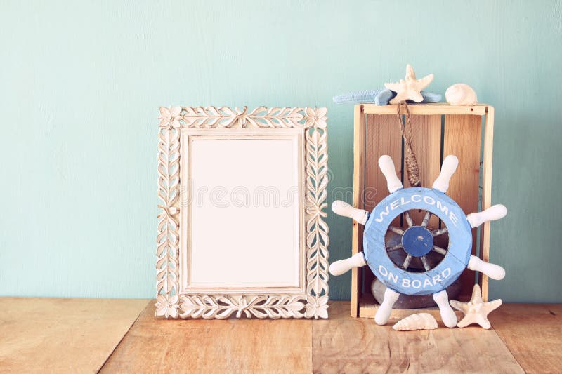 Old vintage frame with naurical wheel on wooden table. vintage filtered image. Old vintage frame with naurical wheel on wooden table. vintage filtered image.