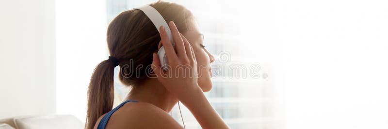 Close up side view woman closing eyes wearing headphones listening music enjoy favorite song resting at home. Leisure concept horizontal photo banner for website header design with copy space for text