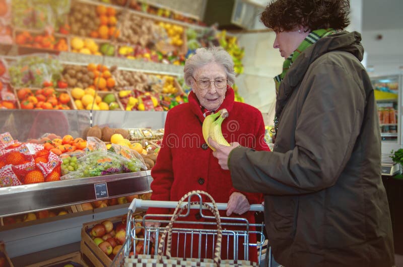 Caregiver helping old senior women in the supermarket with shopping. Caregiver helping old senior women in the supermarket with shopping