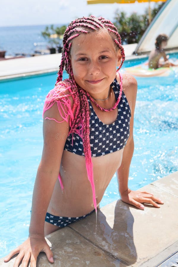 Teenager girl get out from swimming pool, dressed swimsuit and pink dreadlocks on head. Teenager girl get out from swimming pool, dressed swimsuit and pink dreadlocks on head
