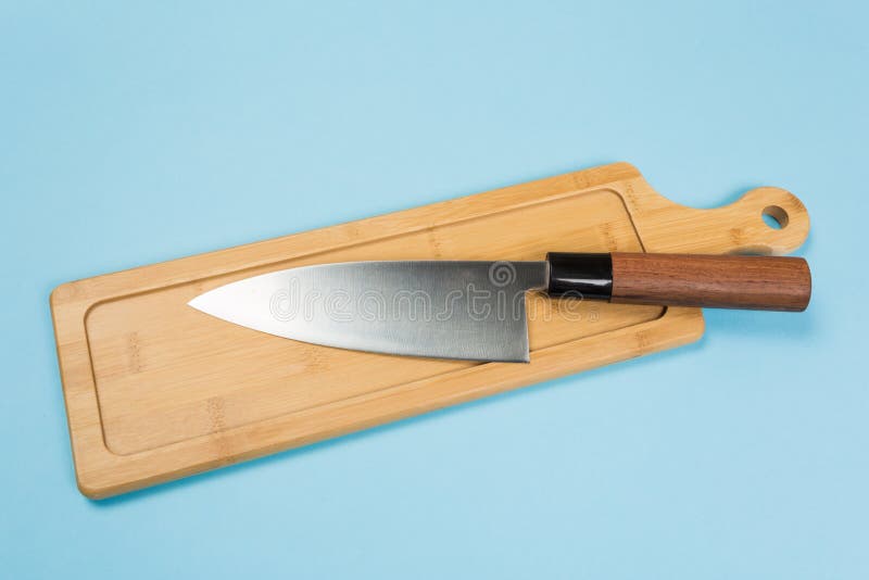 Large stainless steel kitchen knife with brown wooden handle. Big kitchen knife lying on an cutting board