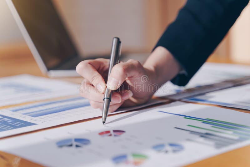 Businesswoman holding pen pointing on summary report chart and calculate finance in office. Businesswoman holding pen pointing on summary report chart and calculate finance in office.