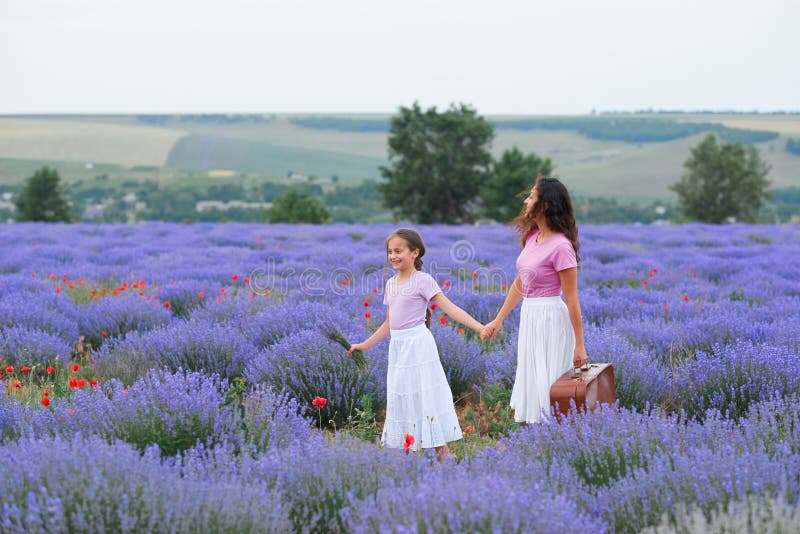 Young women and girl are walking through the lavender flower field, beautiful summer landscape