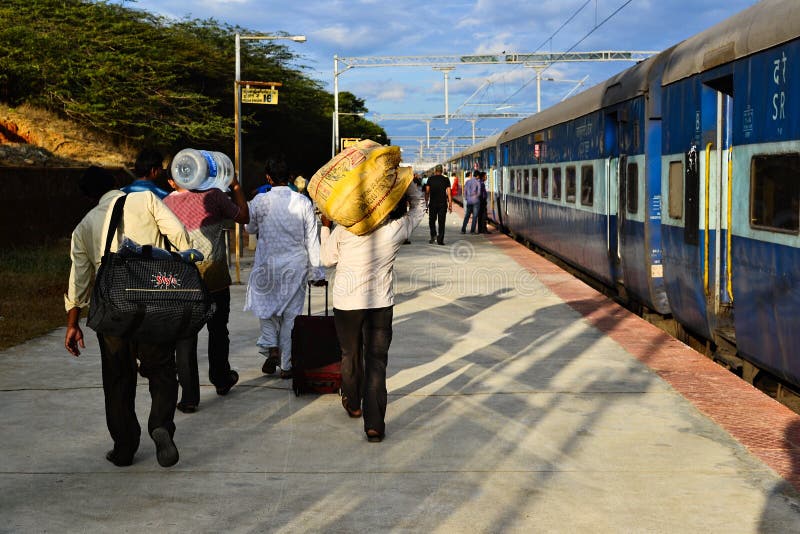 Kanyakumari, Tamil Nadu, India - January, 2017: Group of Indian men walk on platform carrying heavy bags before departure train on the railway station. Kanyakumari, Tamil Nadu, India - January, 2017: Group of Indian men walk on platform carrying heavy bags before departure train on the railway station