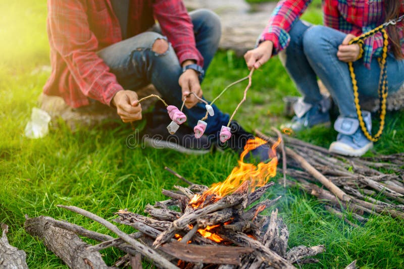 Hands of lover roasting marshmallows over the fire in a grill closeup , Travel concept