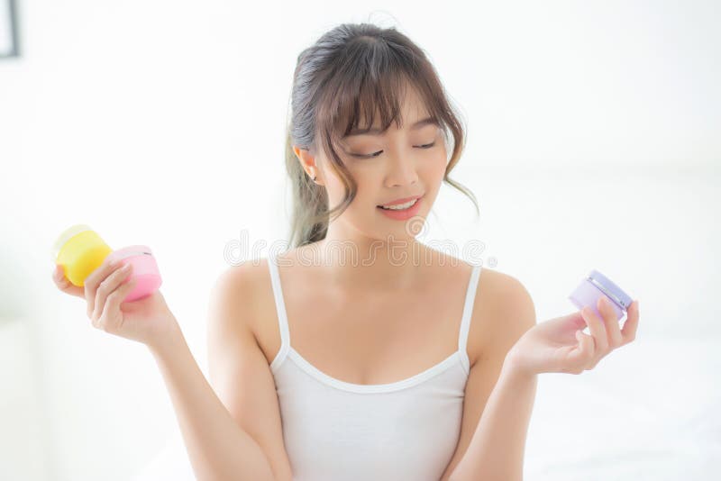 Schönes Porträt einer attraktiven jungen asiatischen Frau, die Gläser mit Creme und Lotion für die Gesichtshaut hält, frisch und w lizenzfreie stockfotografie