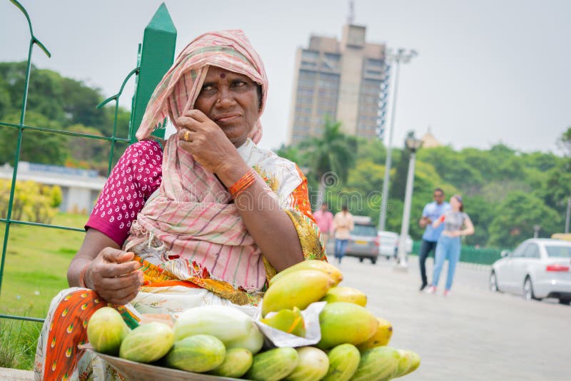Bangalore, Karnataka India-June 04 2019 :Street vendor Woman selling mango`s and cucumber at hot sunny day at Bangalore, India. Bangalore, Karnataka India-June 04 2019 :Street vendor Woman selling mango`s and cucumber at hot sunny day at Bangalore, India.