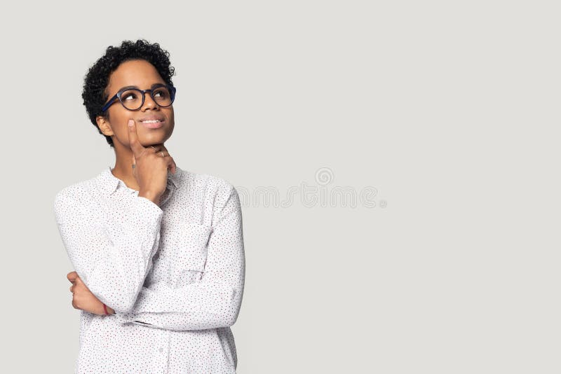 Thoughtful african American girl in glasses isolated on grey studio background look up at blank copy space aside, pensive biracial millennial woman think pondering over sale offer making choice. Thoughtful african American girl in glasses isolated on grey studio background look up at blank copy space aside, pensive biracial millennial woman think pondering over sale offer making choice