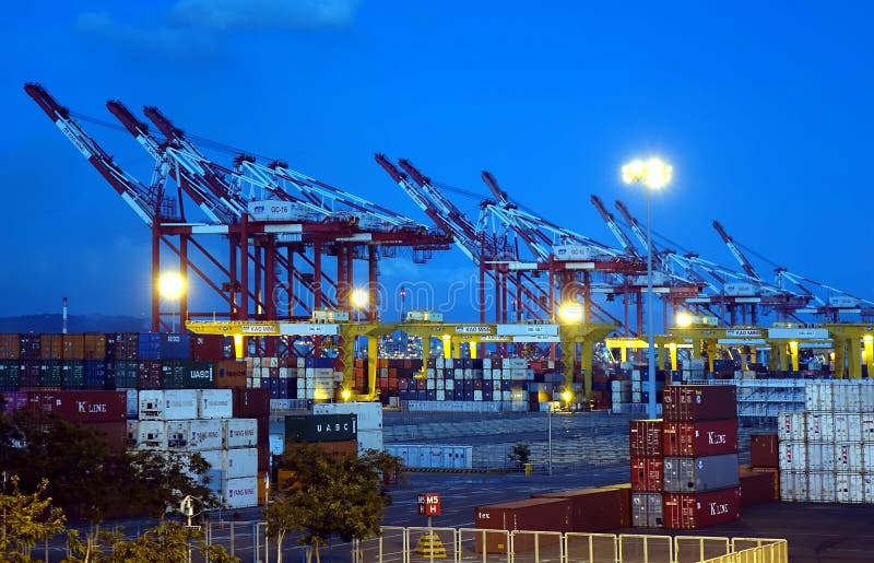 KAOHSIUNG, TAIWAN -- JUNE 2, 2019: Containers are being loaded in Kaohsiung Port at dusk. KAOHSIUNG, TAIWAN -- JUNE 2, 2019: Containers are being loaded in Kaohsiung Port at dusk