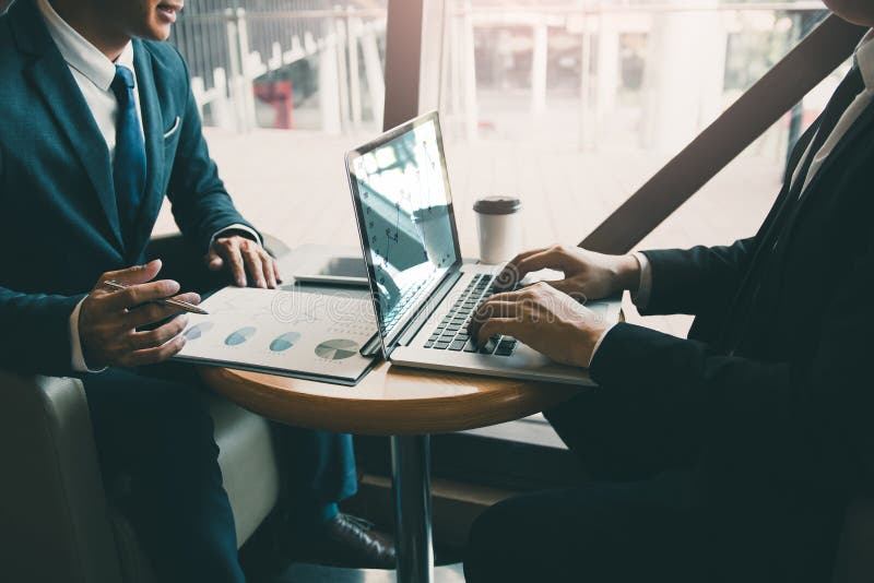 Two businessmen are talking about the results of operations in the company financial statements on the computer screen. Two businessmen are talking about the results of operations in the company financial statements on the computer screen.