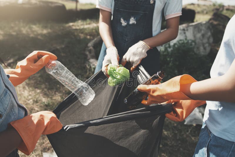 people picking up garbage and putting it in plastic black bag for cleaning at park. people picking up garbage and putting it in plastic black bag for cleaning at park