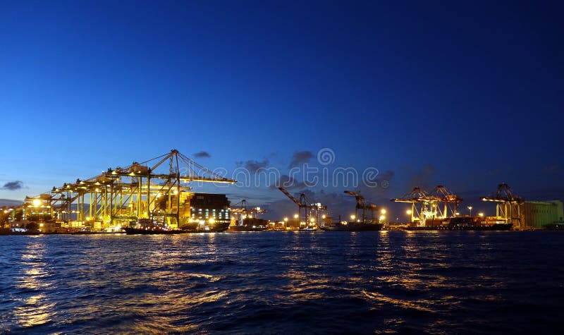 KAOHSIUNG, TAIWAN -- JUNE 2, 2019: Containers are being loaded onto ships in Kaohsiung Port at dusk. KAOHSIUNG, TAIWAN -- JUNE 2, 2019: Containers are being loaded onto ships in Kaohsiung Port at dusk