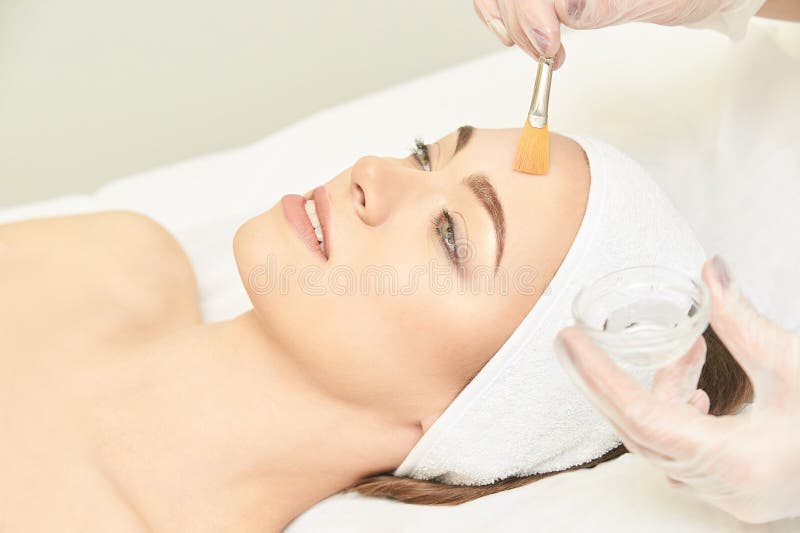 Traitement de rétinol à brosse faciale Procédure d'écorçage de la femme de beauté Cosmetologie thérapie de la petite fille Acide photo stock