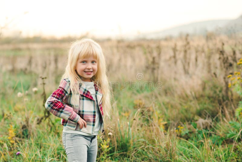 Petite fille mignonne avec de longs cheveux blonds et yeux stupéfiants sur le fond de nature Enfant élégant de mode dehors Heureu photos stock Petite fille mignonne avec de longs cheveux blonds et yeux stupéfiants sur le fond de nature Enfant élégant de mode dehors Heureu photos stock