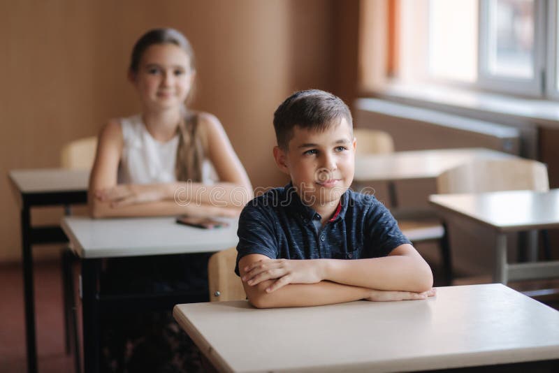 Lyckliga små barn i grundskola Pojkar och flickor studerar Barn lyfter upp handen royaltyfri foto Lyckliga små barn i grundskola Pojkar och flickor studerar Barn lyfter upp handen royaltyfri foto