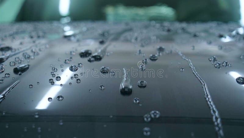 At the car wash, after washing, water drops and wax flow down the windows. Concept of: Window cleaning, Special Cleaning products, Professional work. At the car wash, after washing, water drops and wax flow down the windows. Concept of: Window cleaning, Special Cleaning products, Professional work.