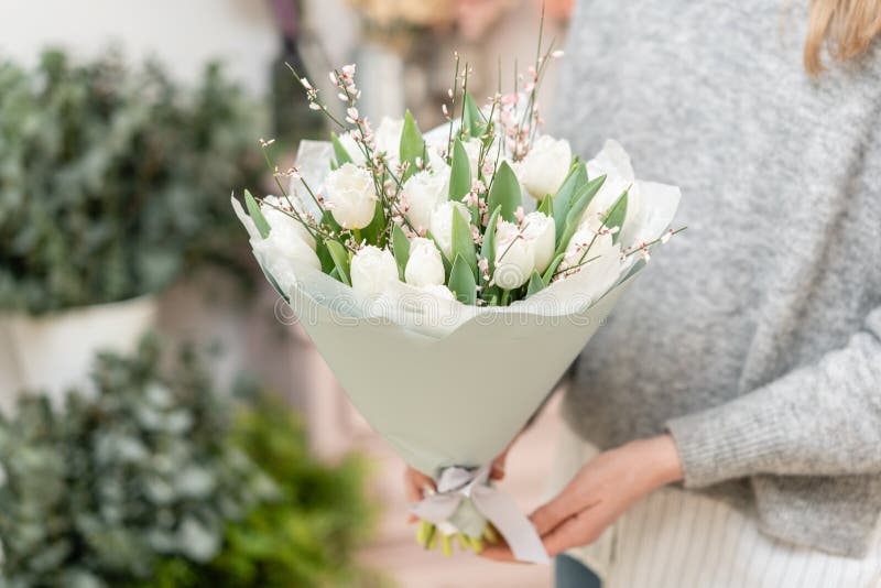 Vackra kakor av vita tulpanblommor i kvinnohand blommornas arbete i en blomsterbutik söt fin flicka