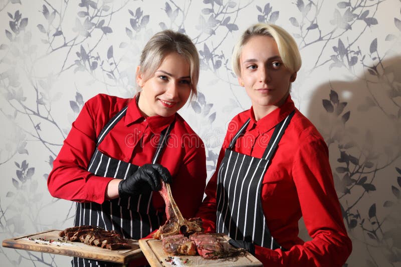 Mädchen mit Steaks mittelgeröstetes Steak auf einem Holzbrett mit Soße und Würzen Rindensteinsteak auf Holz lizenzfreie stockbilder