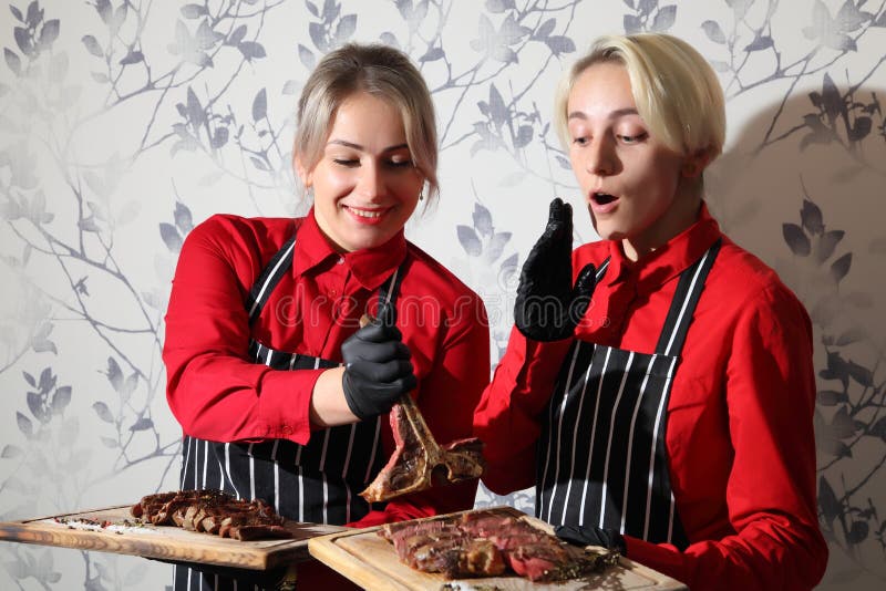 Mädchen mit Steaks mittelgeröstetes Steak auf einem Holzbrett mit Soße und Würzen Rindensteinsteak auf Holz lizenzfreie stockbilder