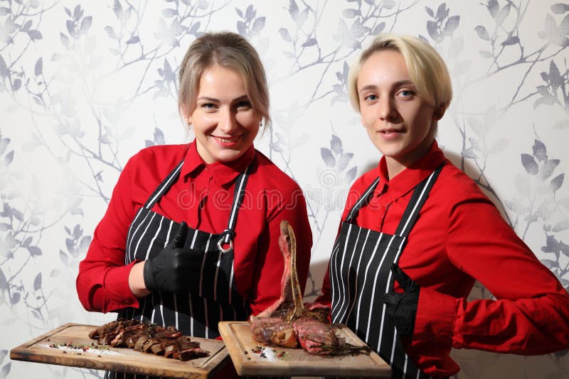 Kellnerinnen mit Steaks. Medium-gebratenes Steak, in Stücke geschnitten auf einem Holzbrett mit Soße und Gewürzen. Rindersteak auf stockfotografie