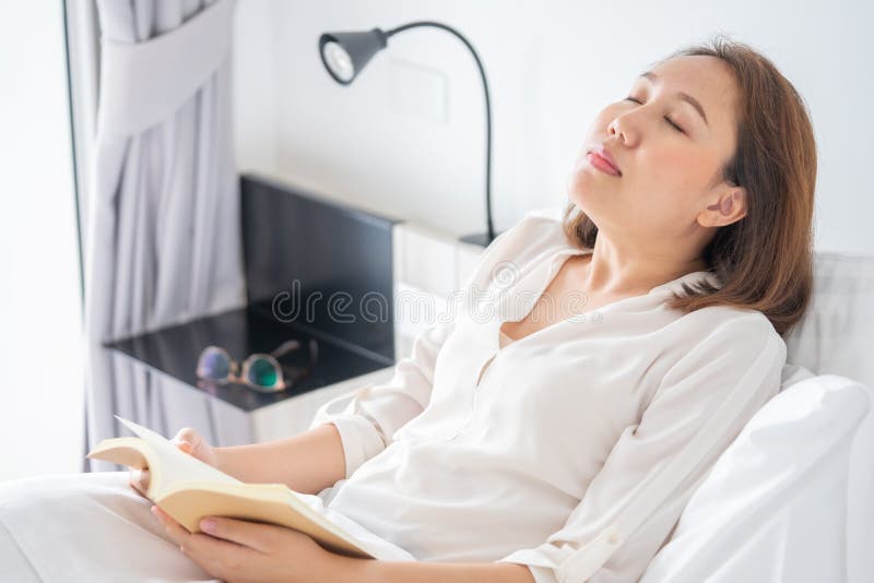 Asian girl Read books while sleeping. Man book cover Drowsiness causes sleep.The concept of adequate sleep. Asian girl Read books while sleeping. Man book cover Drowsiness causes sleep.The concept of adequate sleep.