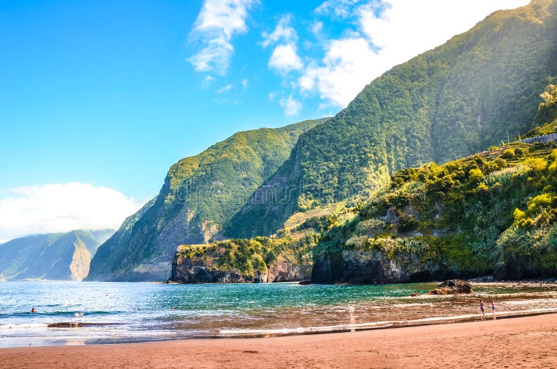 Prachtig zandstrand in Seixal, Madeira, Portugal. Groene heuvels bedekt met tropisch woud op de achtergrond. Mensen op het strand royalty-vrije stock afbeelding