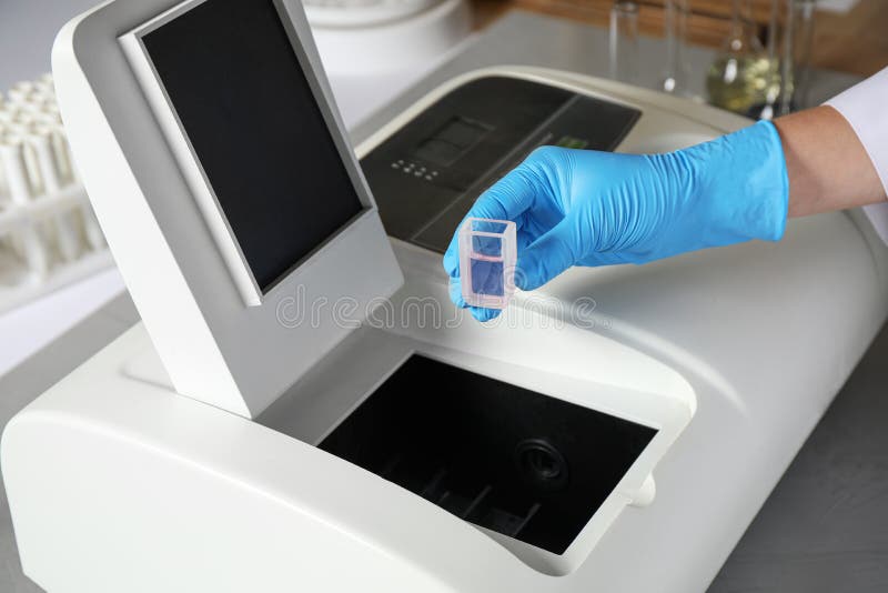 Scientist putting sample compartment with liquid in spectrophotometer, closeup. Laboratory analysis. Scientist putting sample compartment with liquid in spectrophotometer, closeup. Laboratory analysis