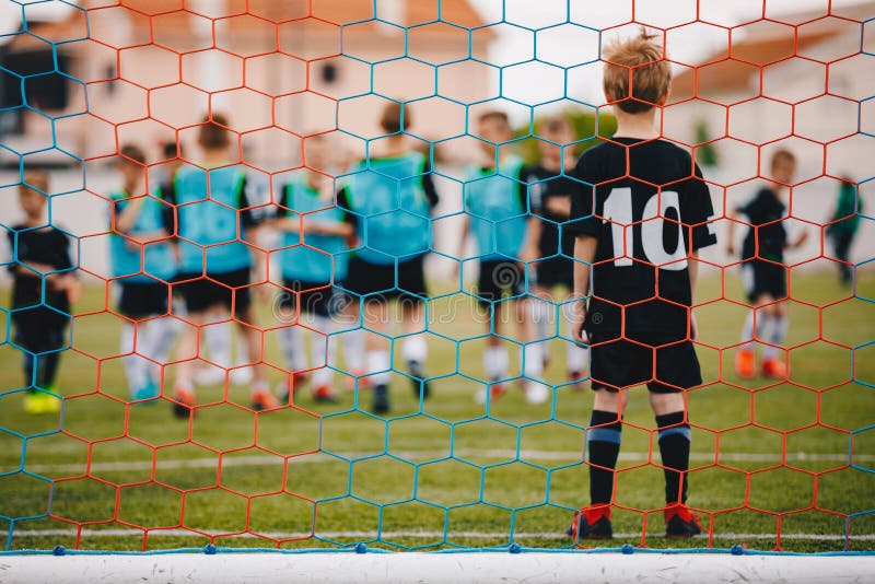 Back of Children Football Player Junge Junge im Fußball-Ziel Low-Angle-Bild von hinter dem Zielnetz stockfotografie Back of Children Football Player Junge Junge im Fußball-Ziel Low-Angle-Bild von hinter dem Zielnetz stockfotografie