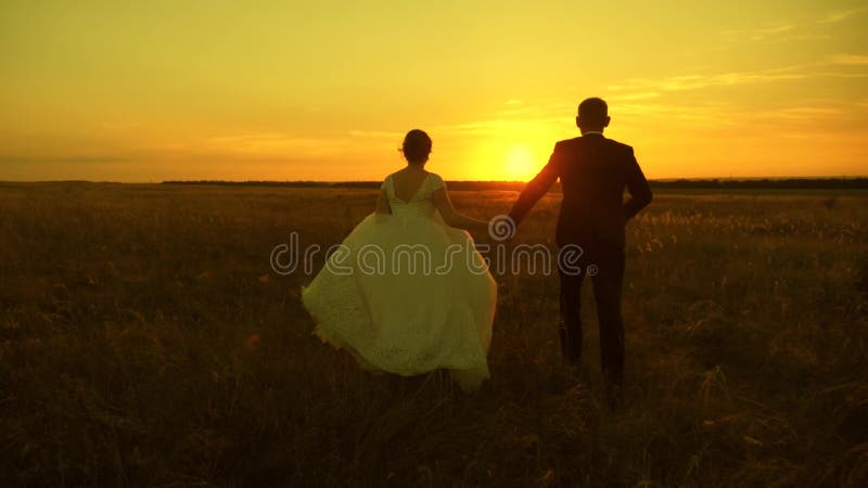 Een paar in liefde handen vasthouden gaat naar zonsondergang Vrolijke man en vrouw rennen op zonsondergang Een paar verliefd op e