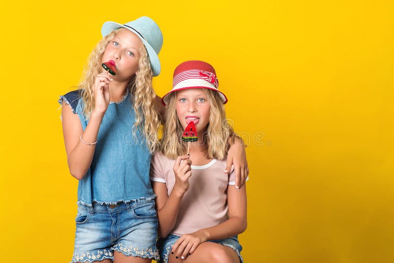 Glad tvillingsystrar på sommarhattar Tonåringar, flickor, med gul bakgrund Strålar i snygga sommarutrustningar Funniga flickor arkivbild Glad tvillingsystrar på sommarhattar Tonåringar, flickor, med gul bakgrund Strålar i snygga sommarutrustningar Funniga flickor arkivbild