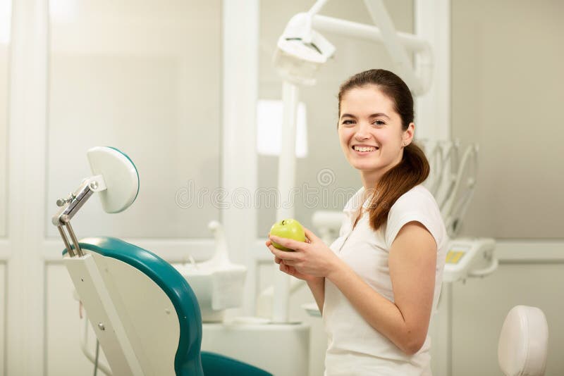 ?e?ski dentysta u?miecha si? i trzyma zielonego jab?ka, stomatologicznej opieki i zapobiegania poj?cia obraz royalty free ?e?ski dentysta u?miecha si? i trzyma zielonego jab?ka, stomatologicznej opieki i zapobiegania poj?cia obraz royalty free