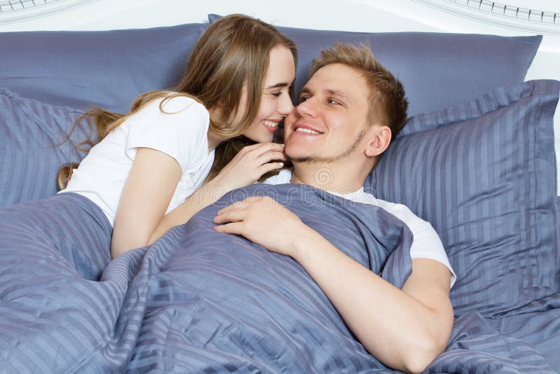 E Unga vuxna heterosexuella par som ligger p? s?ng i sovrum royaltyfri fotografi E Unga vuxna heterosexuella par som ligger p? s?ng i sovrum royaltyfri fotografi