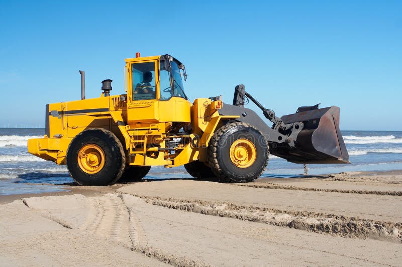 Action shot of an orange digger moving earth at the beach. Action shot of an orange digger moving earth at the beach.