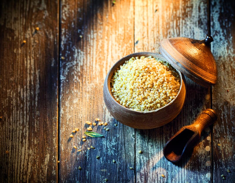 High angle view of a rustic earthenware pot filled with dried bulgur, a popular Middle Eastern ingredient made from cracked or crushed durum wheat. High angle view of a rustic earthenware pot filled with dried bulgur, a popular Middle Eastern ingredient made from cracked or crushed durum wheat