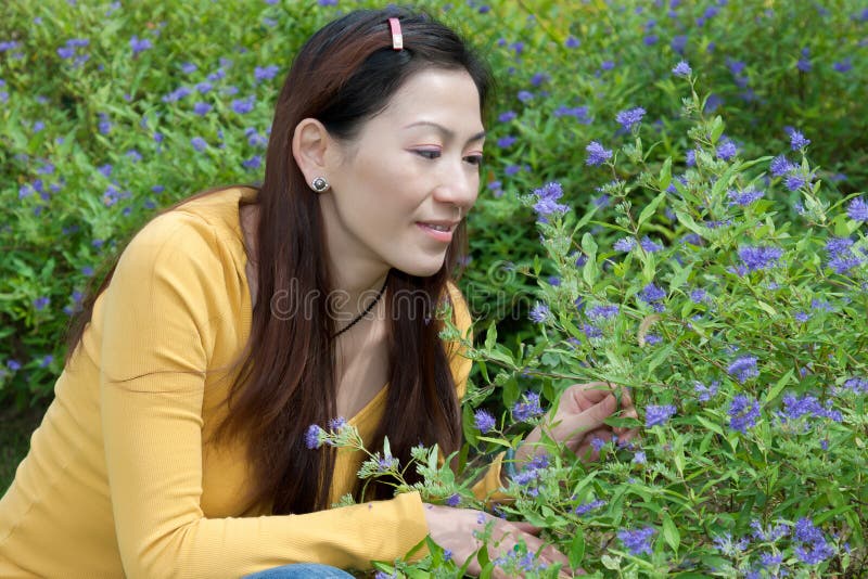 East asian woman squatting to pick flowers