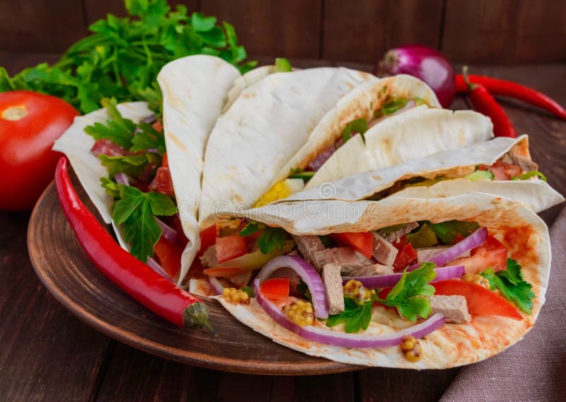 East pita bread with various fillings (meat, salami, egg, cucumber, parsley, tomato, chili pepper, Dijon mustard). Taco.