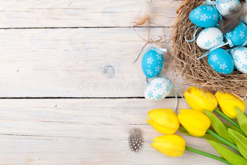 Easter background with colorful eggs and yellow tulips