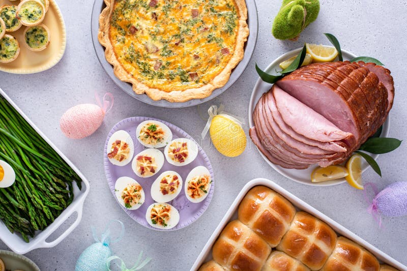 Easter brunch on large table with spiral sliced ham, quiche, deviled eggs and hot cross buns royalty free stock photography