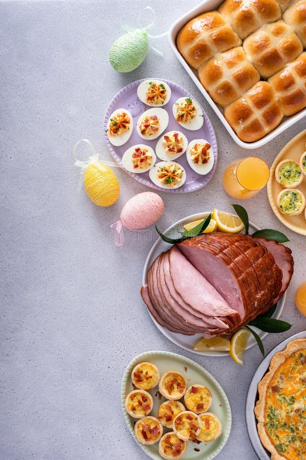 Easter brunch on large table with spiral sliced ham, quiche, deviled eggs and hot cross buns royalty free stock photo