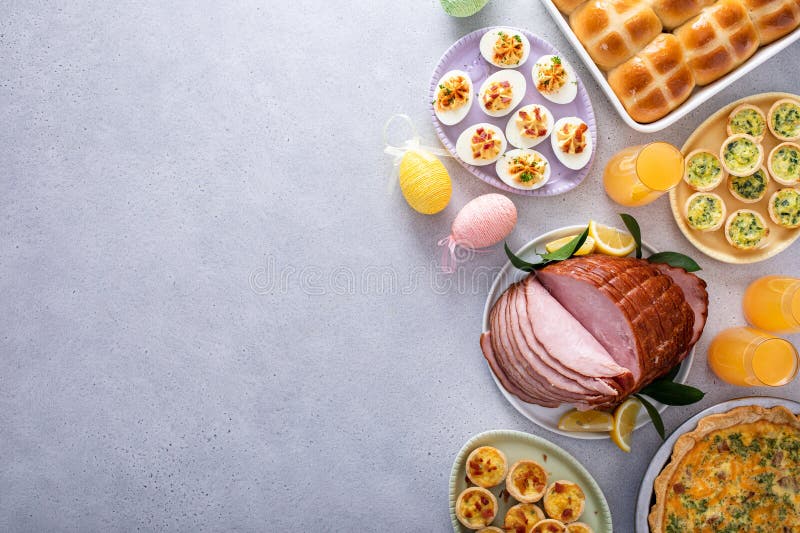 Easter brunch on large table with spiral sliced ham, quiche, deviled eggs and hot cross buns royalty free stock photos