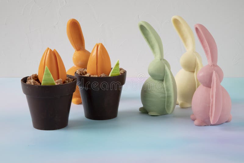 The Easter bunny hid behind flower pots with tulip buds from other funny and cheerful bunnies - a chocolate composition made of