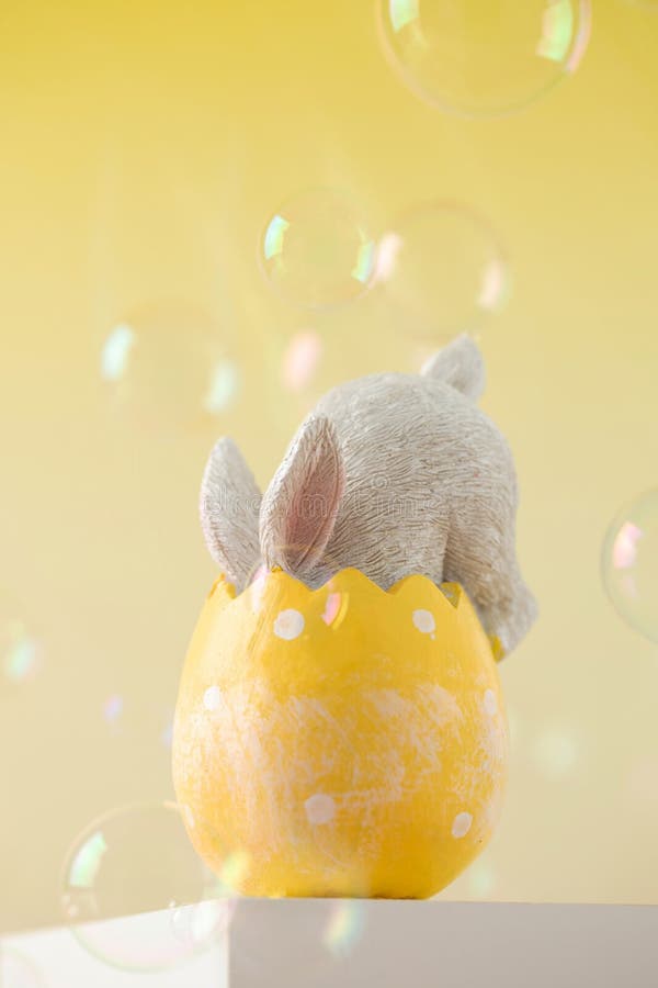 The Easter Bunny Hid in an Egg on a Yellow Background with Flying Soap